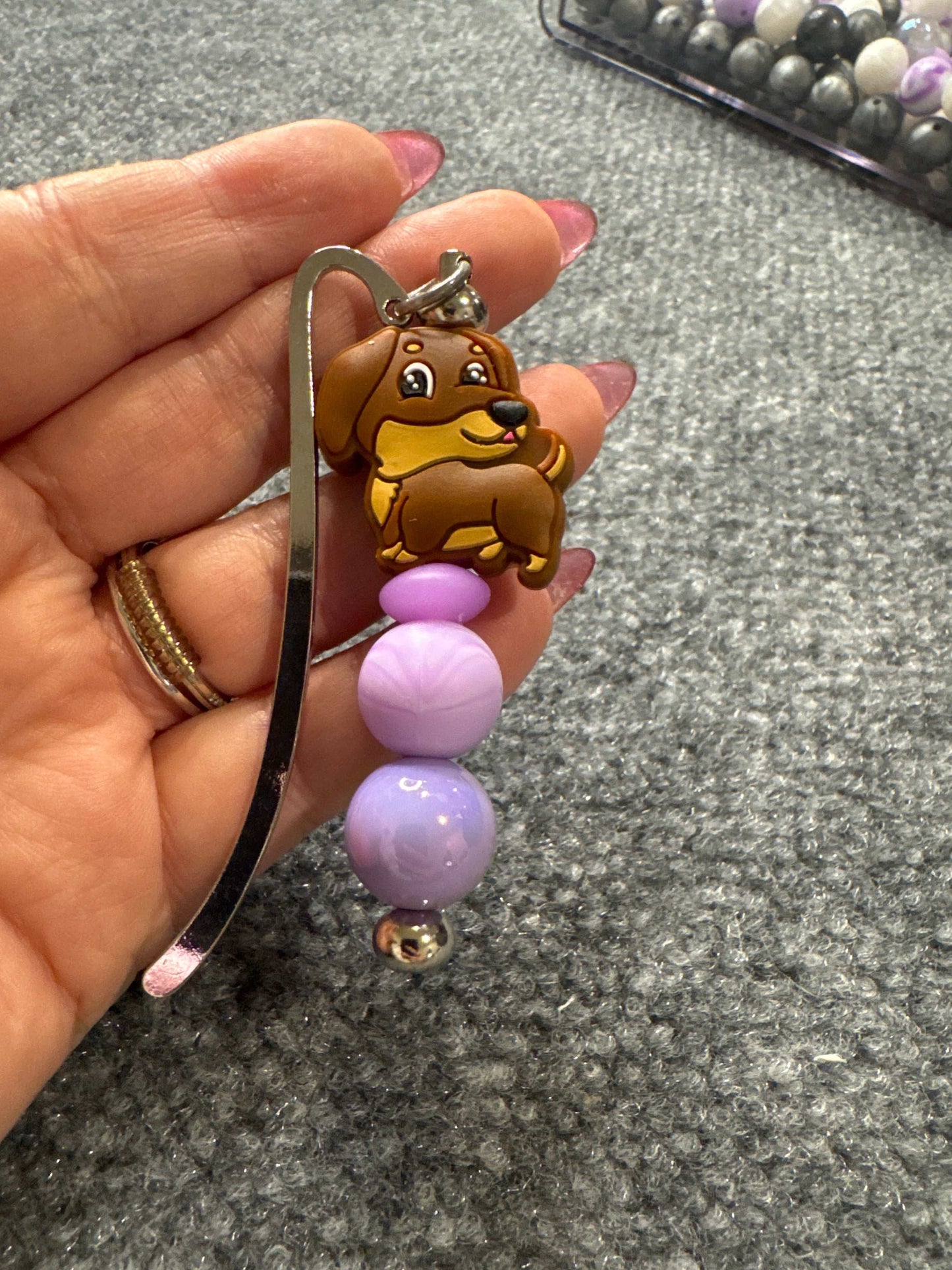 Custom metal book mark with hanging charm placed in an open book