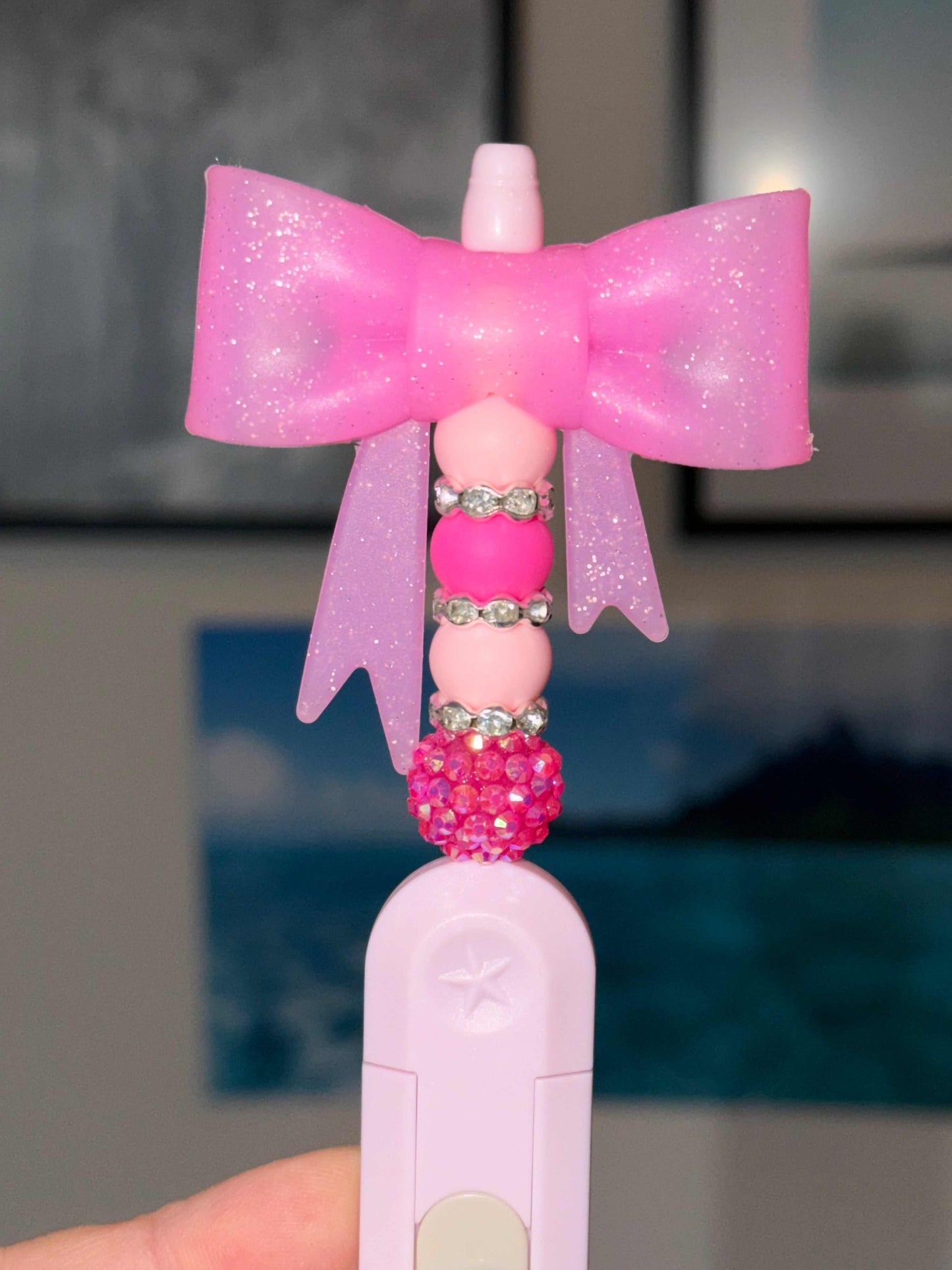 Pink bow and rhinestone retractable box cutter on white background.