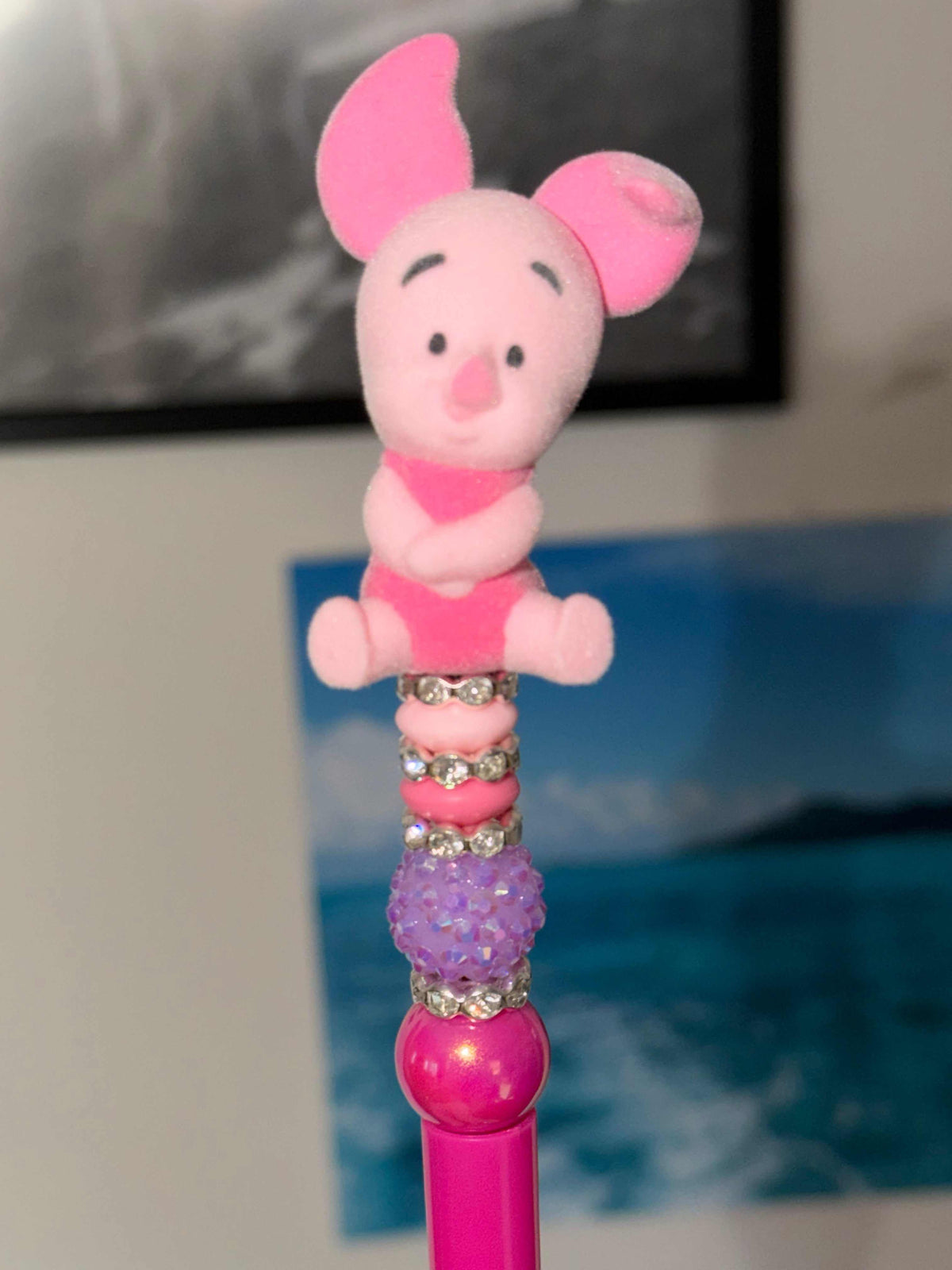 Handmade beaded pen featuring an authentic Piglet Bean character topper with pink beads, rhinestone spacers, a glittery lavender focal bead, and decorative kawaii styling.