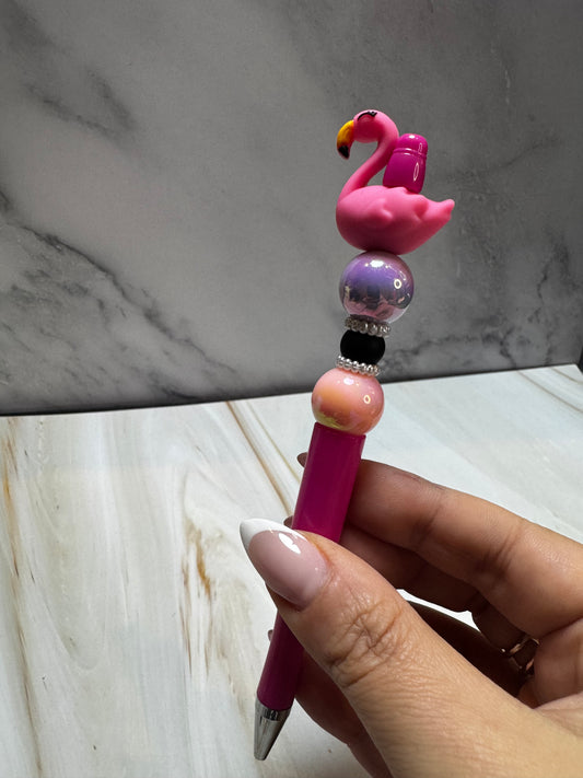 Pink beaded pen with pink, black, and shiny purple beads. A pink flamingo focal bead sits at the top. 