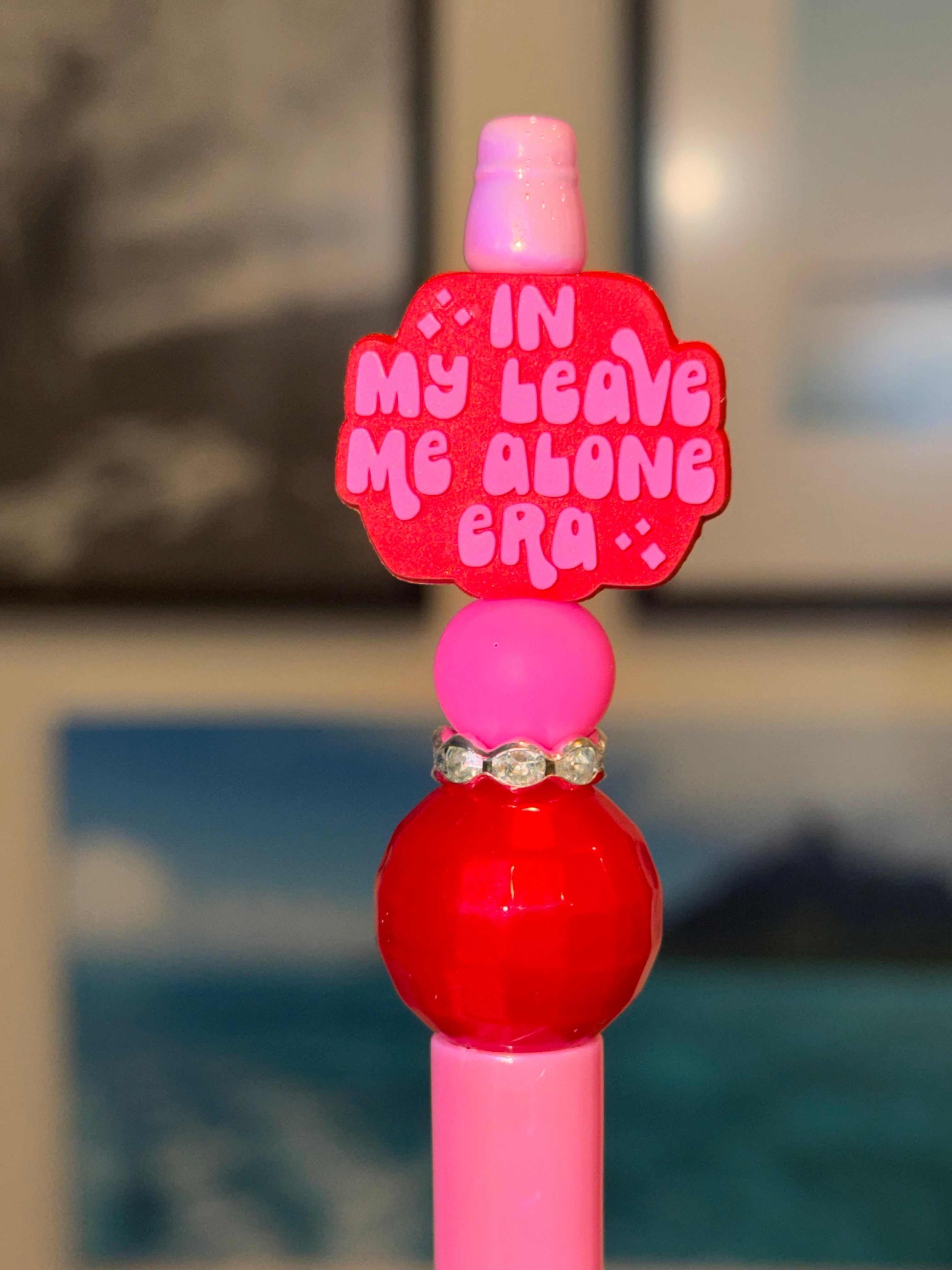 In My Leave Me Alone Era pen with pink and red beads and glitter charm topper