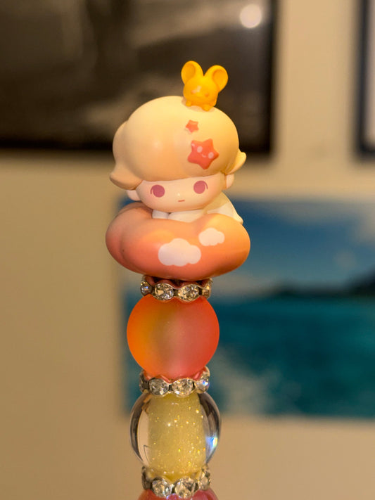 Sunset Dream Beaded Pen with authentic Dimoo Pop Bean figure on peach cloud and sunset-colored beads