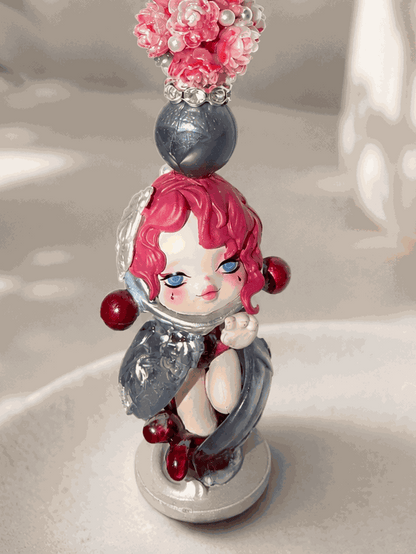 Handmade beaded keychain featuring an authentic pink-haired collectible doll charm with pink floral resin beads, gray pearl accents, sparkling rhinestone spacers, and silver hardware displayed on a neutral background.