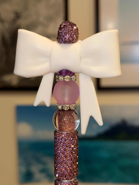 Purple rhinestone beaded pen with white bow and purple crystal accents on a sparkly purple barrel