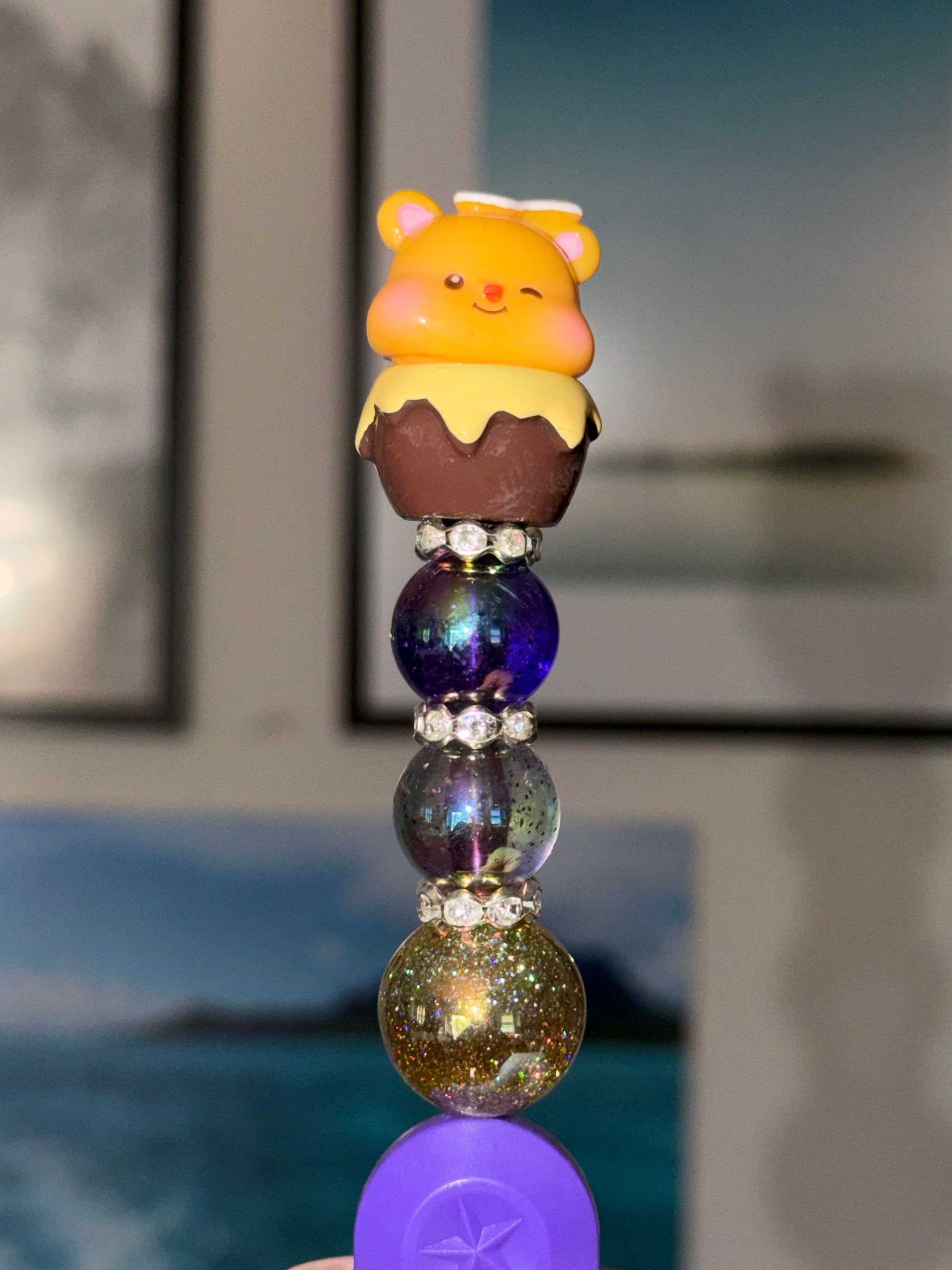 Handmade beaded purple box cutter topped with a yellow golden bear with honey focal, deep purple galaxy orb bead, smoky speckled galaxy bead, and gold holographic glitter orb, separated by crystal rhinestone rondelles.