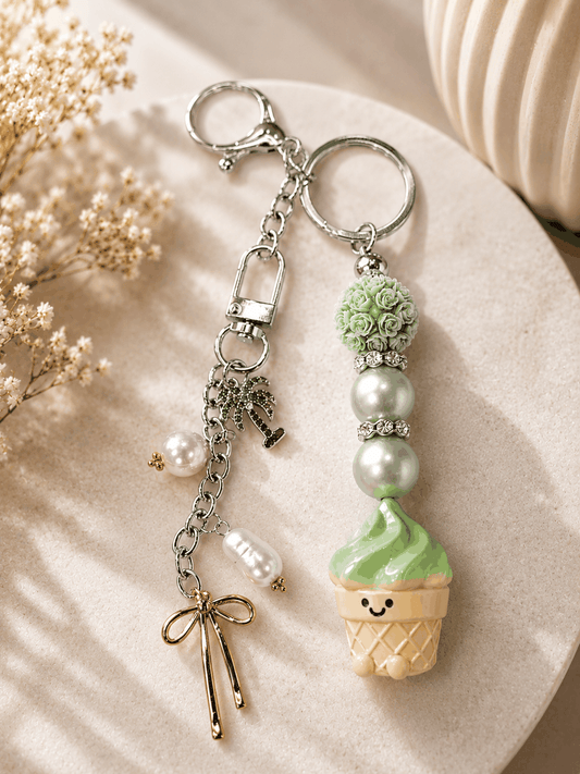 Authentic Meichai Ice Cream Cone handmade beaded bag charm keychain featuring a smiling mint green ice cream cone charm, mint pearl beads, a floral resin bead, rhinestone spacers, genuine freshwater pearl dangles, a palm tree charm, gold bow charm, and silver keyring with lobster clasp.