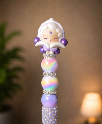Handmade beaded pen featuring an authentic Skullpanda Pop Bean collectible topper with lavender accents, iridescent rainbow beads, sparkling rhinestone spacers, and a pearl-and-crystal embellished pen barrel.