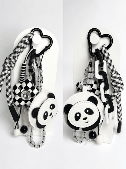 Black-and-white panda bag charm with checkered flower charm, crystal beads, heart carabiner, and gingham wristlet accent.
