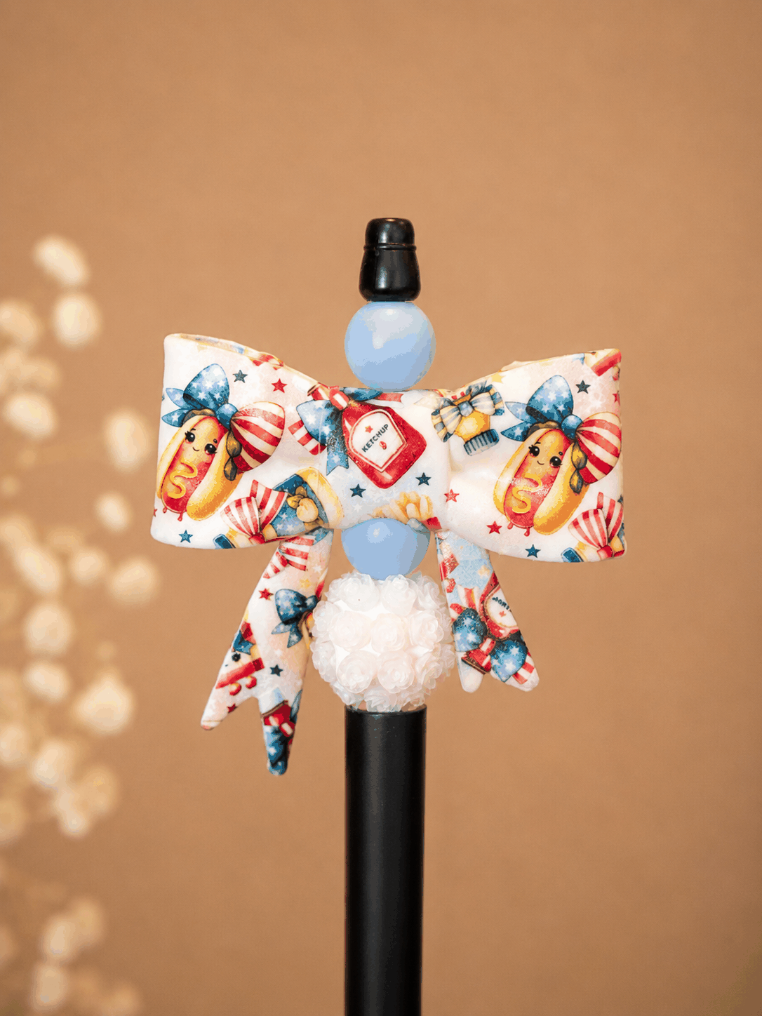 Handmade patriotic hot dog bow pen with summer-themed beads and floral accents on white background