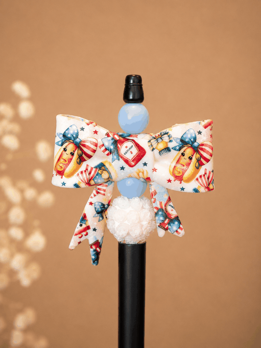 Handmade patriotic hot dog bow pen with summer-themed beads and floral accents on white background