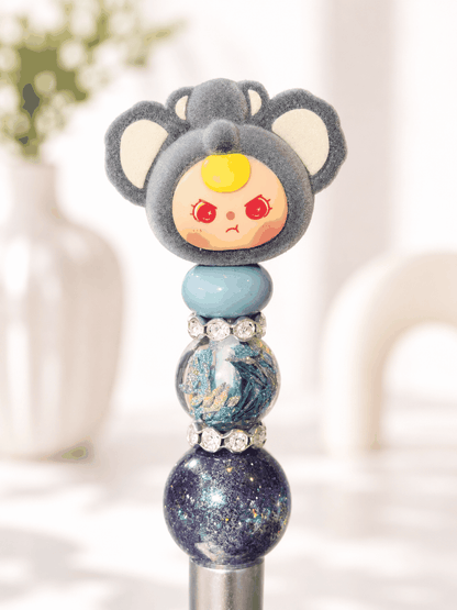 Handmade Baby Three Koala beaded pen featuring an authentic gray koala character topper, blue accent bead, galaxy-inspired decorative beads, and rhinestone spacers.