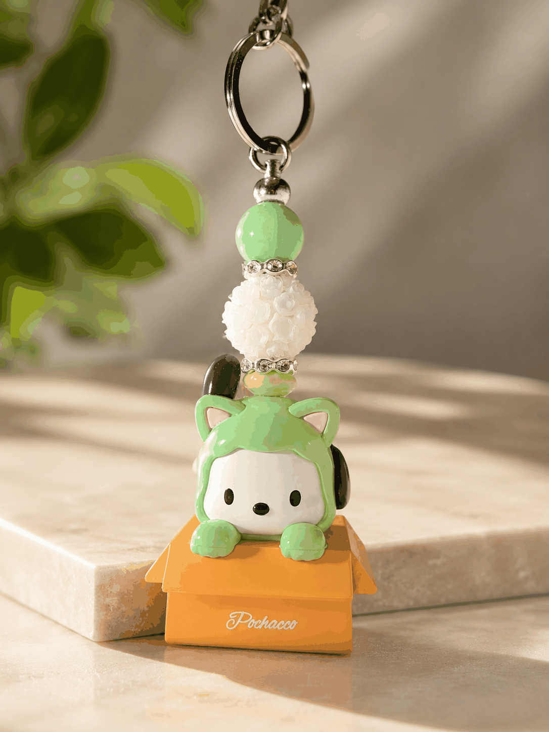 Authentic Pochacco bean bag charm keychain featuring a Pochacco character in a green cat costume with mint green beads, floral bead accents, rhinestone spacers, and a silver keyring displayed on a professional neutral background.