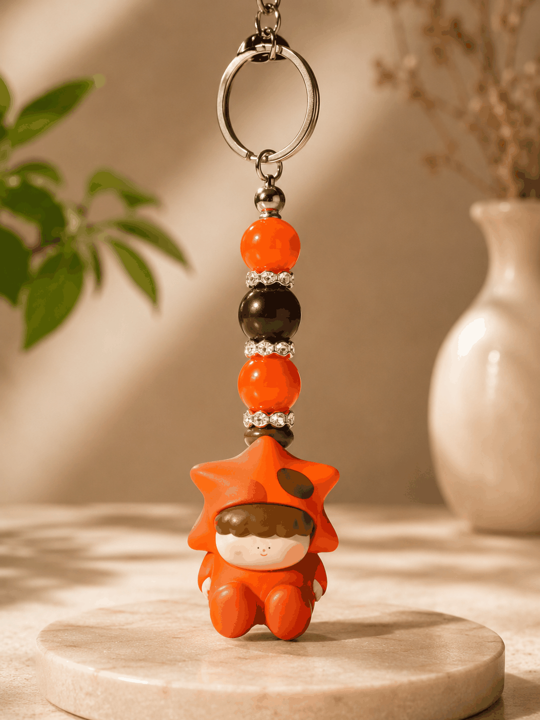 Authentic Amlls bean bag charm keychain featuring a cute orange star costume character with orange and brown beads, rhinestone spacers, and a silver keyring on a neutral background.