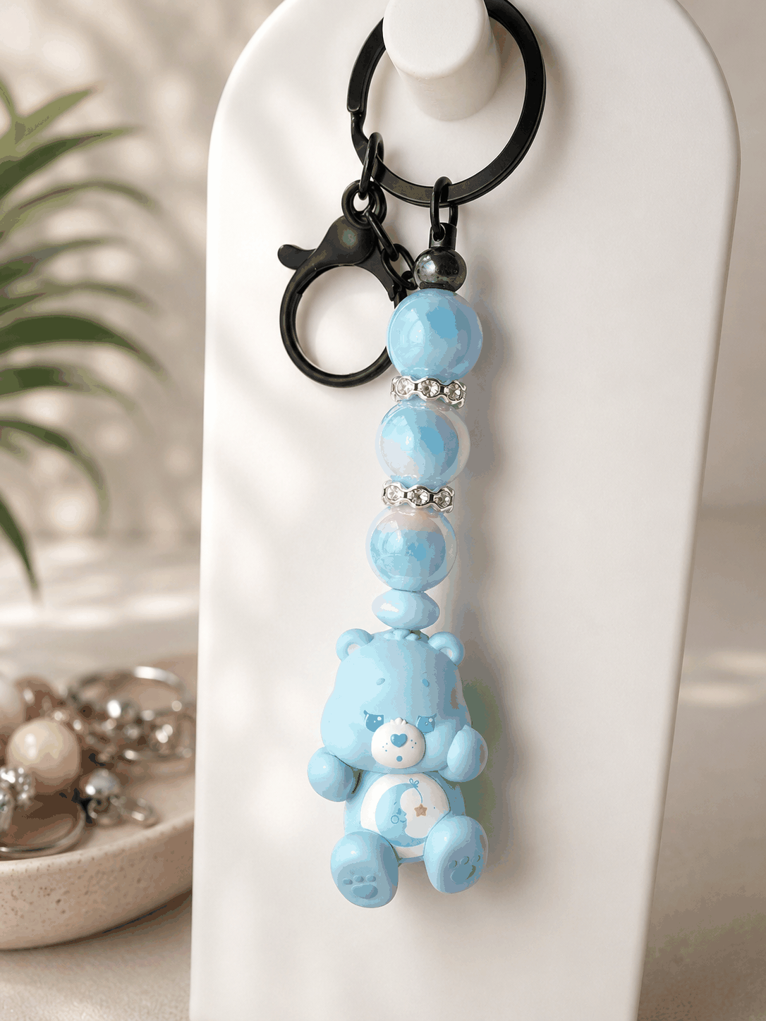 Authentic Care Bears Bedtime Bear beaded keychain featuring a blue Bedtime Bear bean bag charm with pastel iridescent beads, rhinestone spacers, and black hardware displayed against a neutral background.