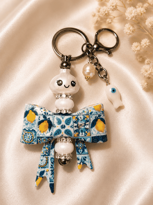 Handmade glitter dumpling bag charm with Mediterranean lemon tile bow, rhinestones, pearl, and evil eye fish accessory